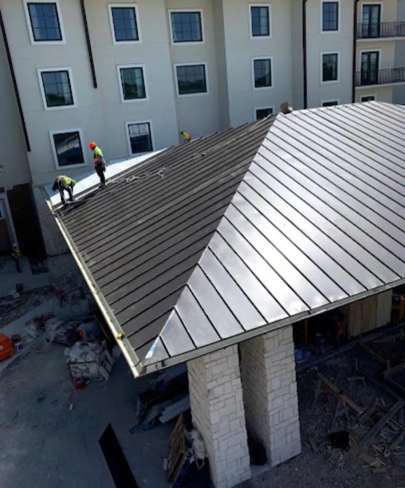 Crew installing standing seam metal roof panels on a commercial project in Carmel